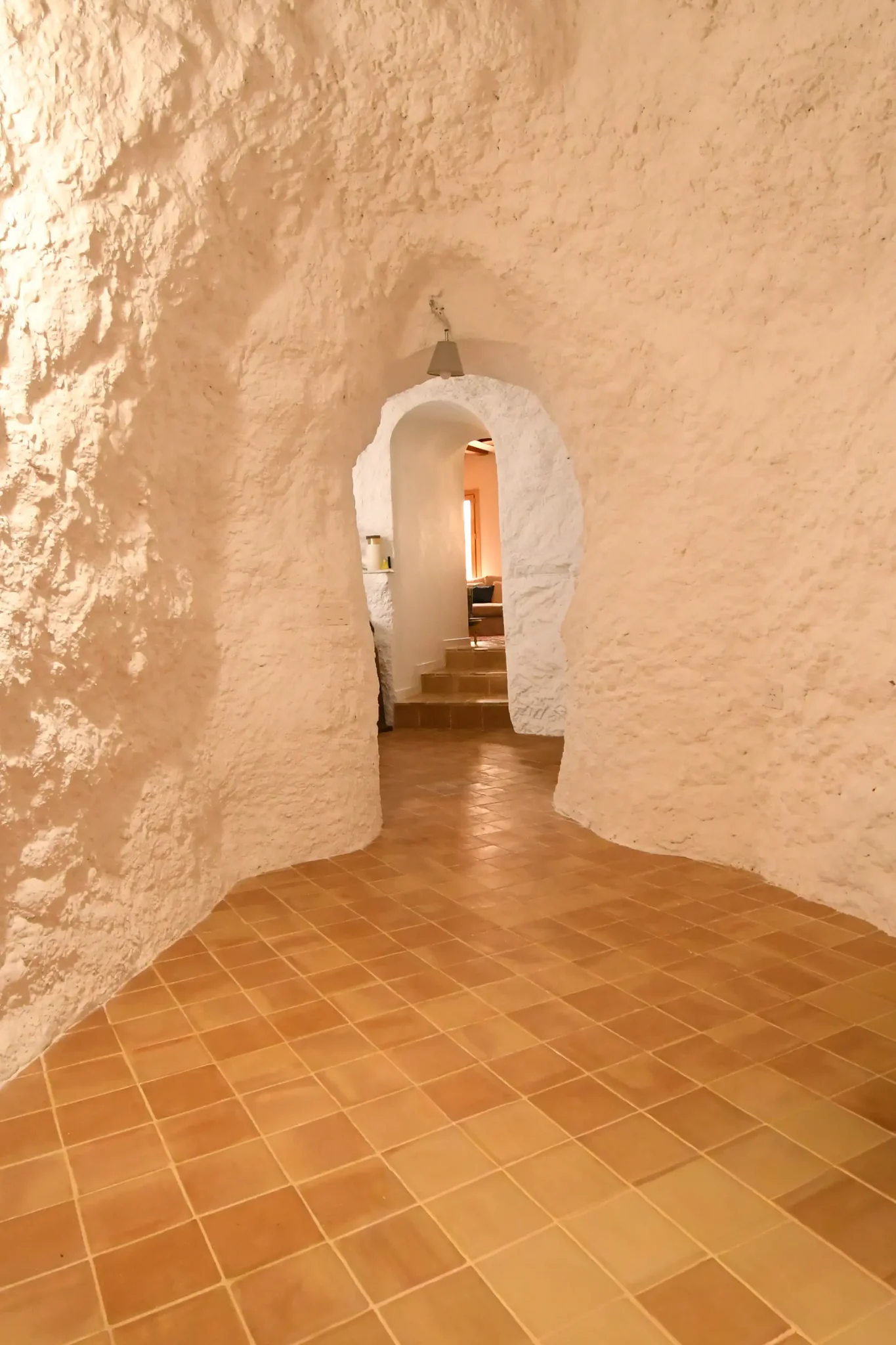 Pasillo excavado en la roca con arco y suelo de barro de la casa cueva de la Bola de Oro