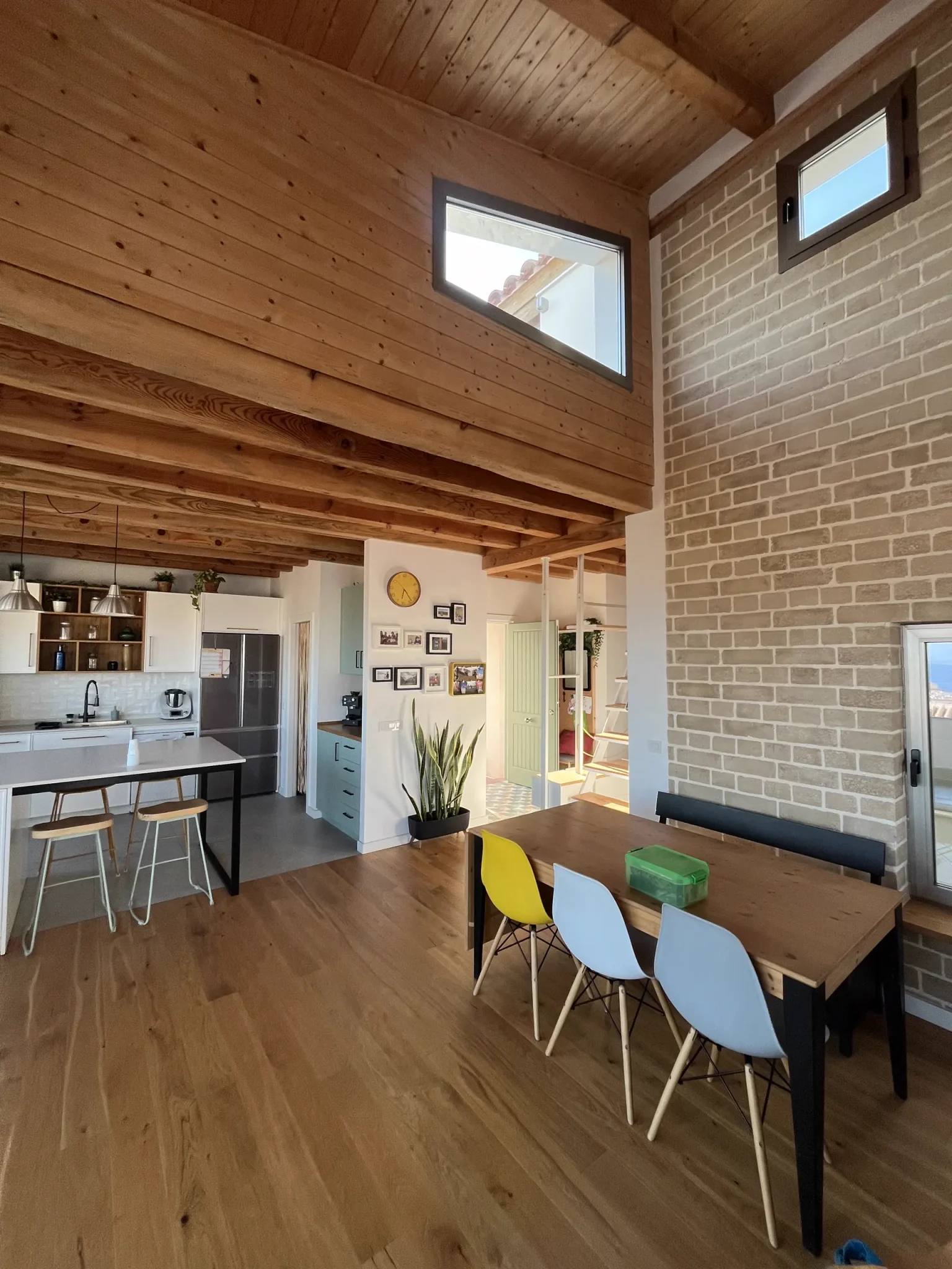 Cocina-comedor con techo de madera y ventanas altas en la casa bioclimática de La Cala del Moral