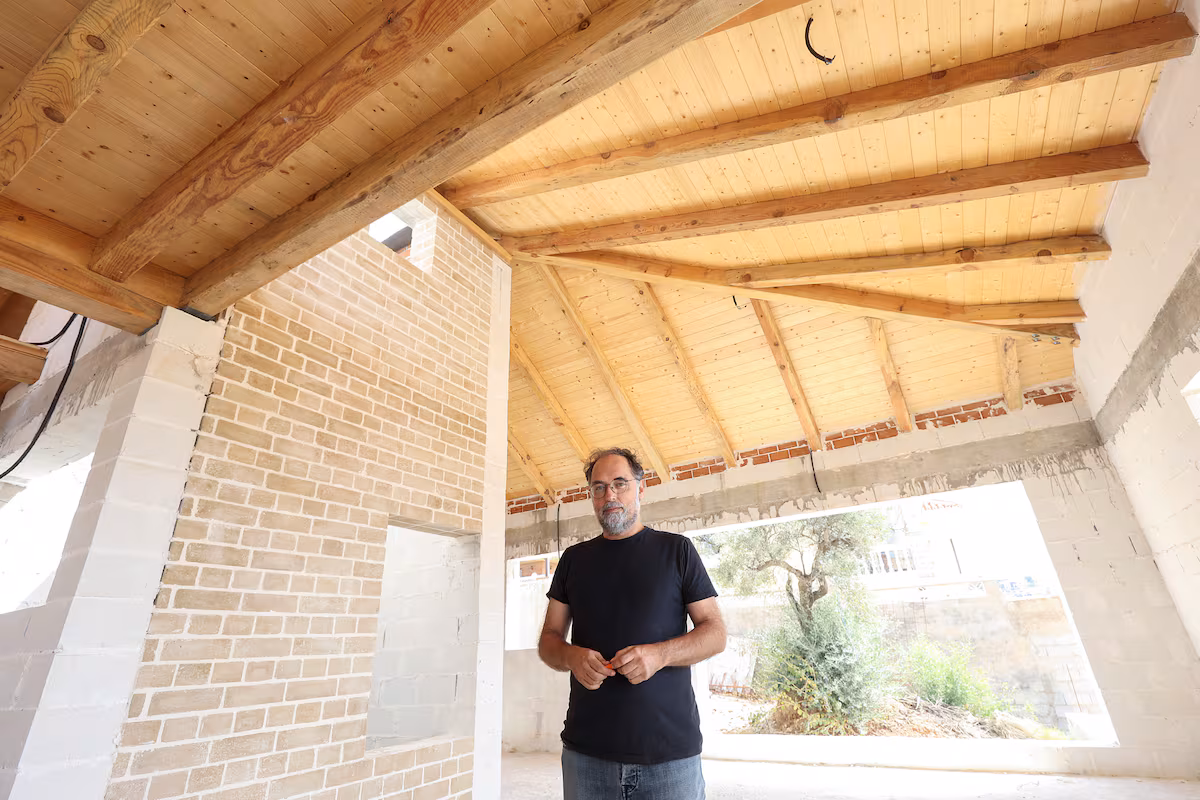 Pablo Farfán bajo una estructura de madera recuperada del incendio de Sierra Bermeja